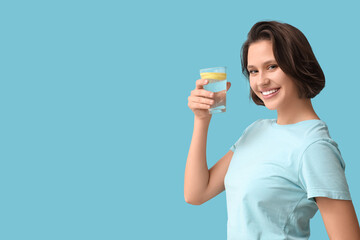 Pretty young woman with glass of infused water on blue background