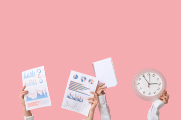 Female hands with diagrams, notebook and clock on pink background. Time management concept