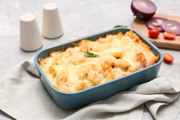 Baking dish with tasty pasta, rosemary and cheese on grey grunge background