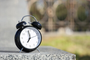 Black alarm clock on concrete outdoors, closeup