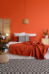 Interior of stylish room with bed, plants and folding screen