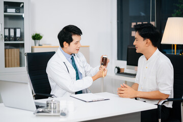 Asian doctor explains prescription medication to male patient during clinical consultation. Health, care, and trust