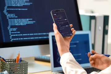 Female programmer's hands working with mobile phone in office, closeup