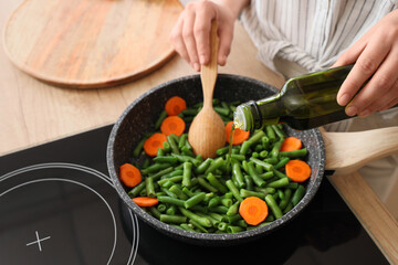Woman with olive oil frying tasty vegetables in kitchen, closeup