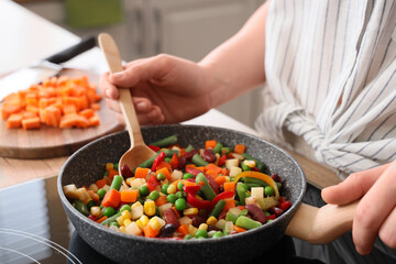 Woman frying tasty vegetables in kitchen, closeup