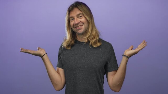 Blond man with long hair holds both palms up and smiles while looking sideways in a studio under purple lighting; uncertainty.