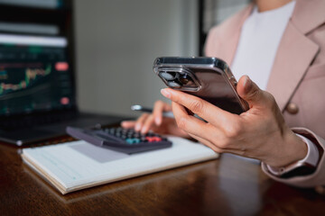 Close-up of businesswoman using smartphone while working with calculator. Concept for accounting and budget planning