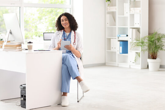 Female African-American medical student using tablet computer at table in office - Powered by Adobe