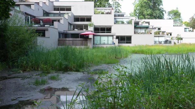 Modern apartment buildings with terraces near green wetland and natural landscap
