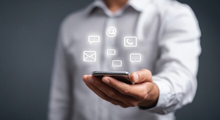 Businessman holds smartphone with communication icons overlaid