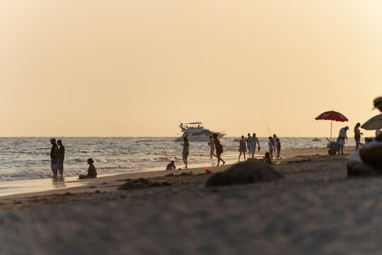Personas disfrutando de la playa al atardecer con yate en el mar