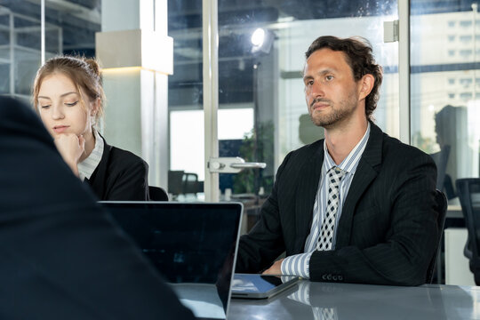 caucasian businessman and female colleague listening during office discussion with asian presenter multiracial business team cooperating and planning project using laptops in modern workspace