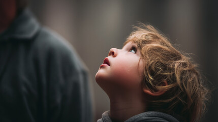 Naklejka premium A young child with blonde hair is looking up at something