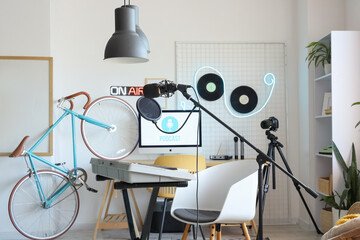 Interior of light podcaster's studio with workplace, synthesizer and bicycle