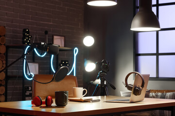 Interior of podcaster's studio with workplace and glowing lamps at night