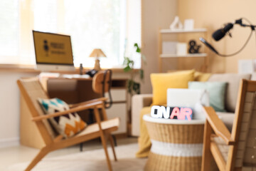 Blurred view of podcaster's studio with workplace, sofa and armchairs