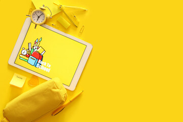 Tablet computer with text BACK TO SCHOOL and stationery on yellow background