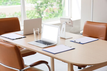 Table with laptops and clipboards prepared for business meeting in conference hall