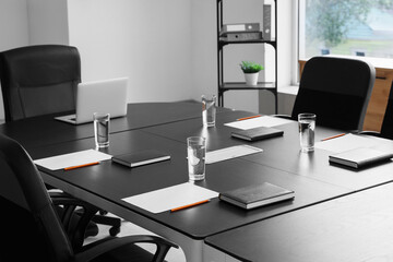 Table with laptop and glasses of water prepared for business meeting in conference hall