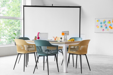 Interior of conference hall with table, projector screen and whiteboard