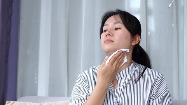 Hyperhidrosis and summer heatwave concept. Asian woman feels hot at home, wiping sweat with tissue paper to stay cool, showing excessive sweating, discomfort, and body heat problems
