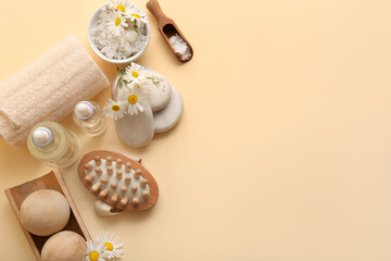 Composition with chamomile flowers, spa stones and bottles of cosmetic products on beige background, closeup