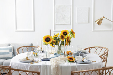 Elegant table serving with plates, candles and beautiful sunflowers in light dining room