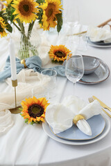 Elegant table serving with plates, folded napkin and beautiful sunflowers, closeup