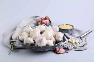 Bowl with fresh garlics and rosemary on grey background