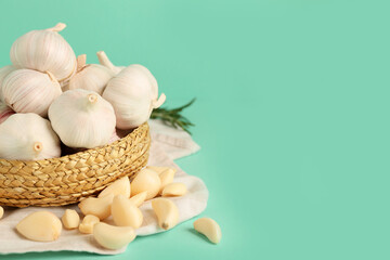Wicker bowl with fresh garlics on turquoise background