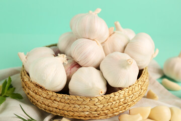 Wicker bowl with fresh garlics on turquoise background