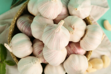 Wicker bowl with fresh garlics on turquoise background, closeup