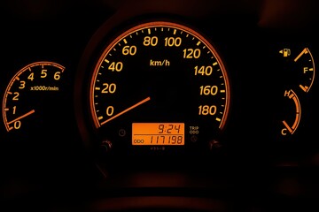 Car dashboard speedometer display vehicle interior digital readout nighttime close-up vehicle performance metrics