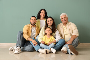 Portrait of big family sitting near green wall