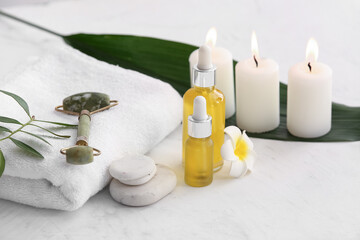 Spa composition with towel, stones and bottles of cosmetic products on white background, closeup