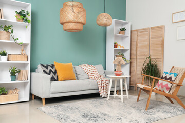 Interior of stylish living room with grey sofa, table and shelf units