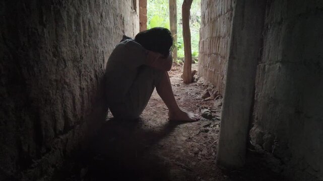 A poor young girl sits in the dark miserable alley of on old house