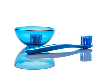 Blue toothbrush and glass bowl on black background
