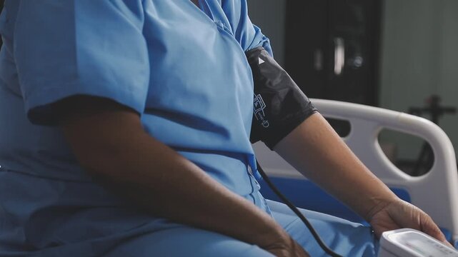 Doctor using sphygmomanometer with stethoscope checking blood pressure to a patient in the hospital.