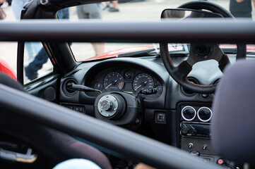A closeup of the interior cockpit of a classic NB car. The JDM sports car is modified with a quick-release steering wheel and a race-spec roll bar.