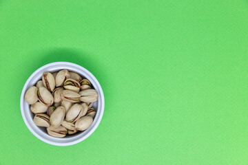 Minimalist composition of pistachio nuts on a green background, highlighting freshness, natural texture, and healthy snack concepts.
