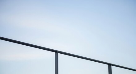 Dark metal railing against pale blue sky black