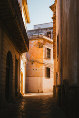 Stone arch and narrow alley in Nardò lit by sunset light