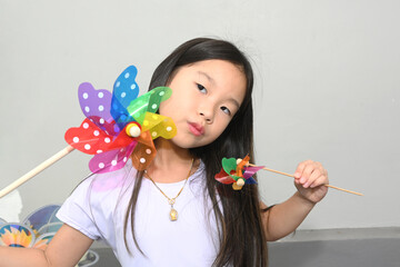 Portrait of a cute Asian girl holding a colourful windmill