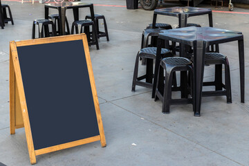 Empty chalkboard next to tables and chairs and a food truck in a square in Brazil