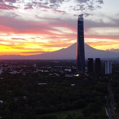 City skyline at sunset with modern tower and volcano