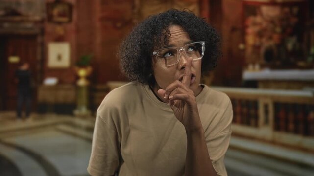 Woman holds finger to lips for silence inside ornate church building interior with carved wooden altar in view; reverence reflection.