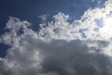 Sun shining through beautiful white clouds in blue sky