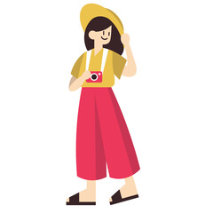 A cheerful female tourist in a yellow hat and red pants, smiling while holding a camera on her vacation.