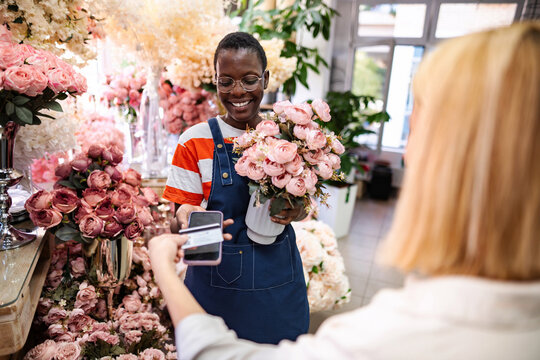 Florist accepting payment via smartphone from customer in flower shop